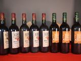 six bottles of red wine are lined up on a red table