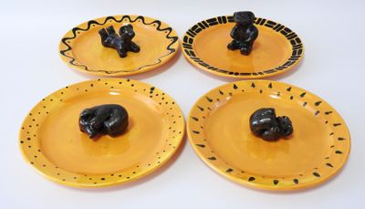 quatre assiettes jaunes ornées d'animaux noirs sur un fond blanc