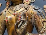 brass statue of a woman holding a bird and a flower