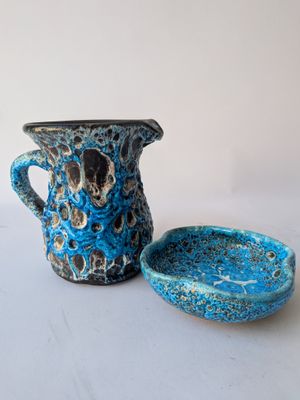 a blue pitcher and a bowl on a white table