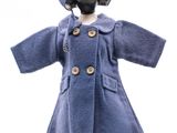 poupée vêtue d'un manteau bleu et d'un chapeau, posée sur un socle de mannequin