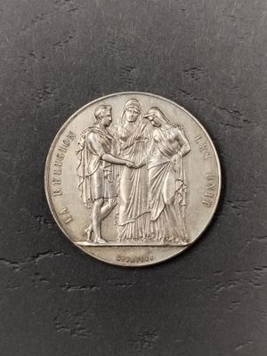 a silver coin with a woman and two men on it