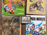 Plusieurs bandes dessinées sont posées sur une table au plateau en bois.