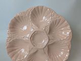a pink plate with a flower on it on a stand