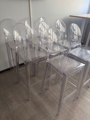 six clear plastic chairs sitting in a row on the floor