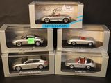 three boxed silver model cars in boxes on a black background