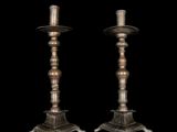pair of antique brass candlesticks on pedestals on a black background