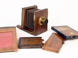 un petit appareil photo en bois à côté d'un petit cadre photo en bois