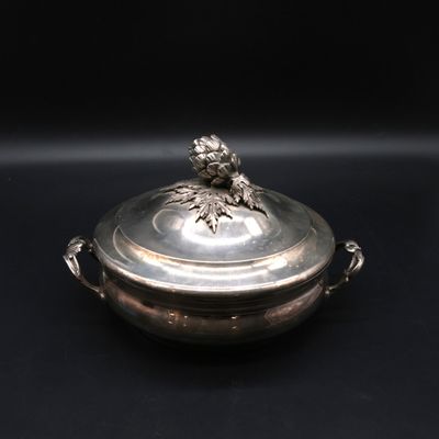 une assiette en argent sur laquelle est représenté un oiseau, sur fond noir