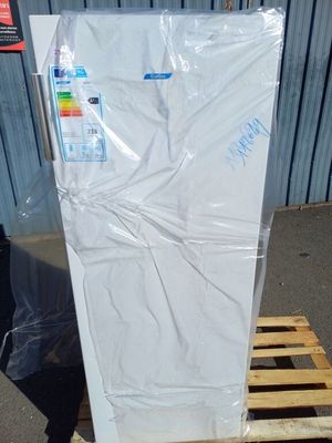 un réfrigérateur blanc posé sur une palette devant un immeuble