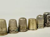 five thimbles lined up in a row on a white surface