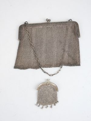 un petit sac à main ancien en maille d'argent muni d'une chaîne, auquel est suspendu un autre petit sac à main en argent muni d'une chaîne