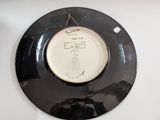 a black plate with a picture on it hanging on a wall