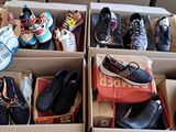 de nombreuses paires de chaussures dans des cartons posés par terre
