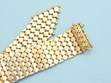 an image of a gold bracelet laying on top of a blue surface