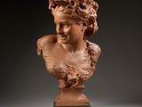 une sculpture représentant une tête de femme posée sur un socle en bois