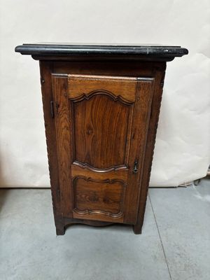 une petite armoire en bois posée au sol, avec un plateau en marbre