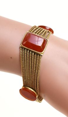 un gros plan sur le bras d'une femme portant un bracelet orné d'une pierre rouge