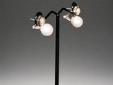 a pair of silver and pearl earrings on a black stand