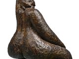 bronze sculpture of a woman sitting on a rock with her legs crossed
