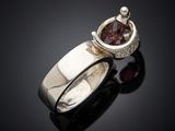 a close up of a silver ring with a red stone in it