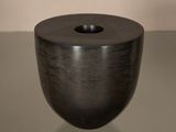 un vase noir posé sur une table, sur fond blanc