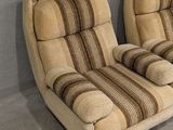 two reclining chairs in a corner of a room with a wall