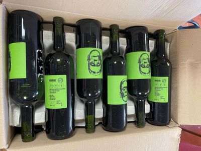 six bottles of wine in a cardboard box on a table