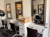 une photo d'un salon de coiffure avec des fauteuils et des miroirs