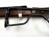 rifle on a white surface with a black handle and a wooden handle