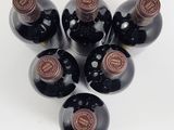 six bottles of wine are arranged in a circle on a white surface