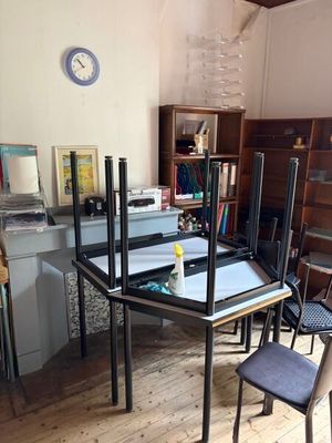 des tables et des chaises dans une pièce équipée de bibliothèques et d'une horloge accrochée au mur