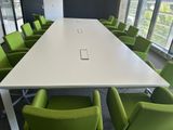 de nombreuses chaises vertes disposées autour d'une table blanche dans une salle de réunion