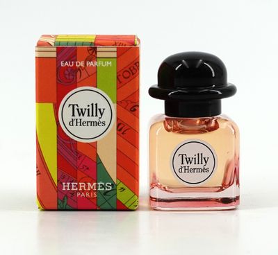un petit flacon de parfum posé à côté d'une boîte