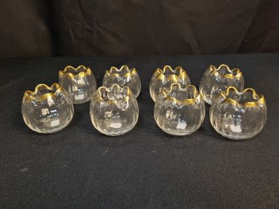 six vases en verre transparent avec des bordures dorées, posés sur un fond noir