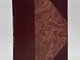 an old book with a brown cover sitting on top of a white surface