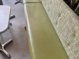 un banc vert au milieu d'une pièce avec des tables et des chaises