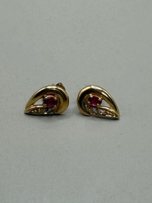une paire de boucles d'oreilles en or et rubis posées sur un fond blanc