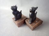 pair of black cat figurines on wooden bases on a white background