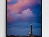 framed photograph of a lighthouse against a cloudy sky at sunset