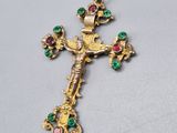 un gros plan d'une croix en or sertie de pierres vertes et roses