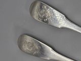 two spoons that are sitting next to each other on a table
