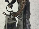 bronze statue of a man working on a piece of metal with a hammer
