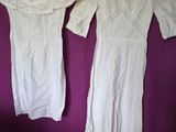 two white dresses hanging on a purple wall with a purple background
