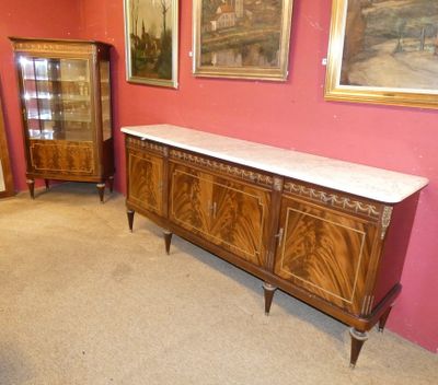 une grande armoire en bois dans une pièce où sont accrochés des tableaux aux murs