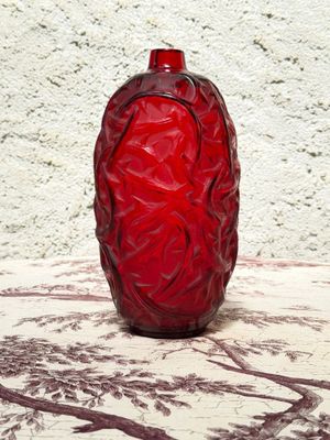a red vase sitting on a table with a white wall in the background