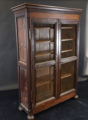an old wooden bookcase with glass doors on a black surface