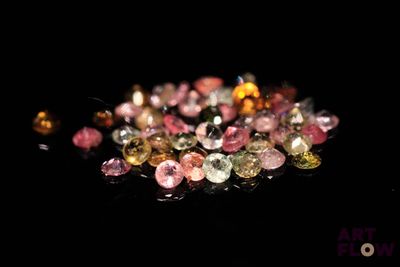 un gros plan sur un tas de diamants de différentes couleurs posés sur une surface noire