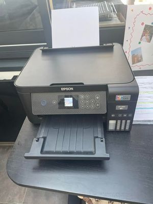 une imprimante noire posée sur un bureau près d'une fenêtre