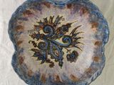 a blue and brown plate with a flower design on it